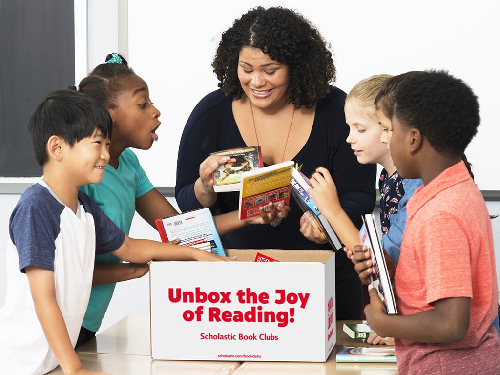 Group of students unboxing books from Scholastic.