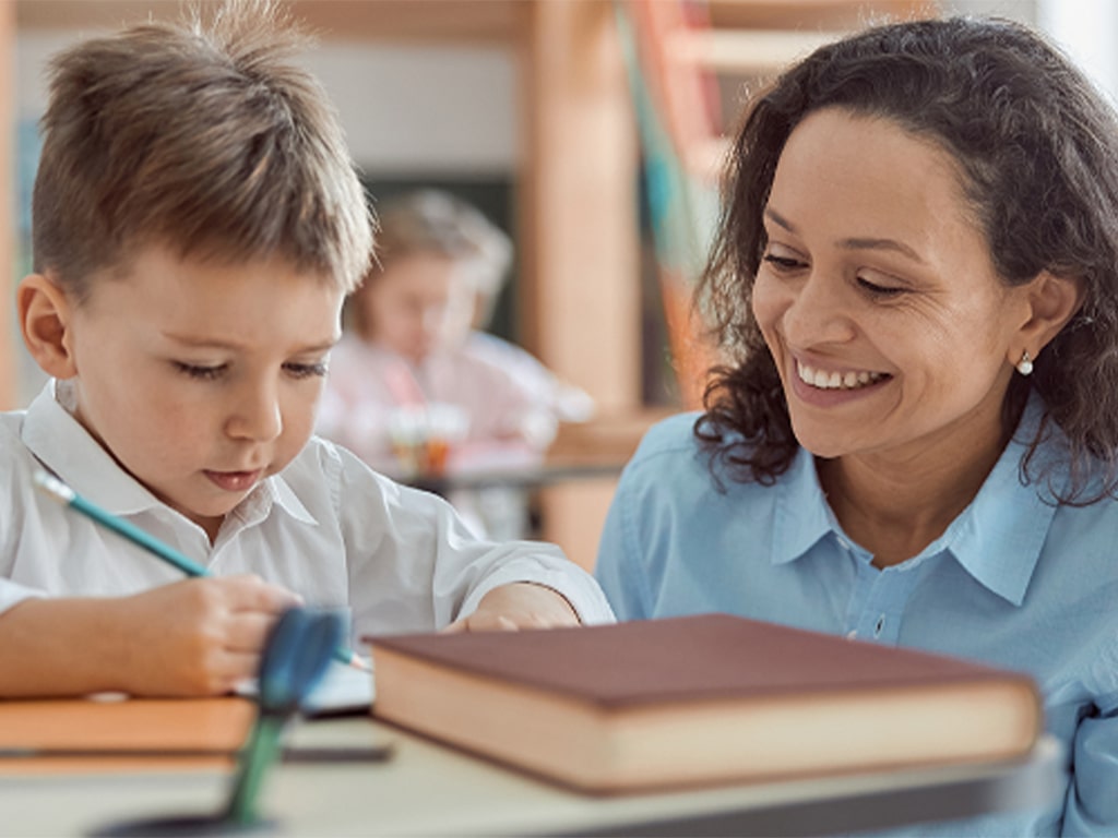Educator with child writing.